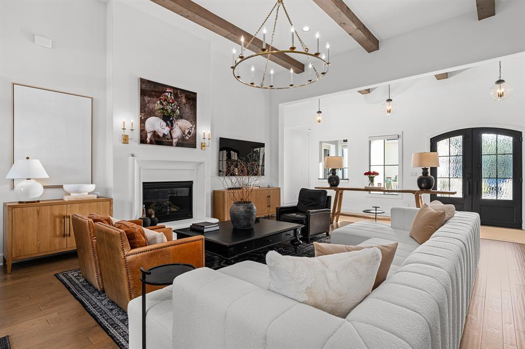 Living room with beamed ceilings, chandelier, and arched iron entry doors