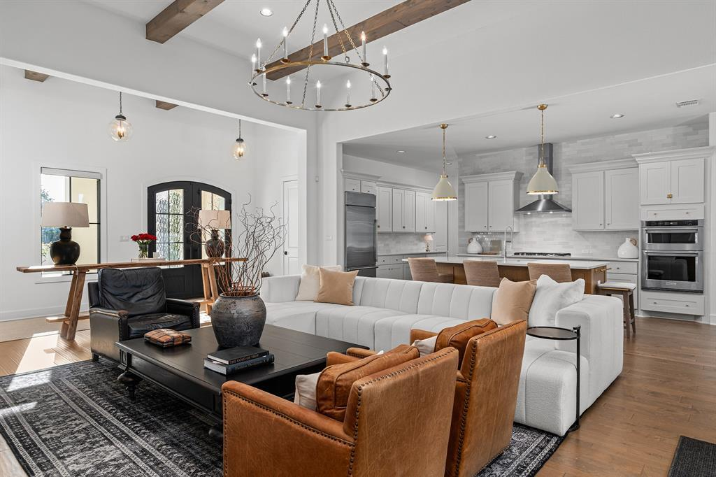 Open-concept living and kitchen — beamed ceilings, island and arched entry