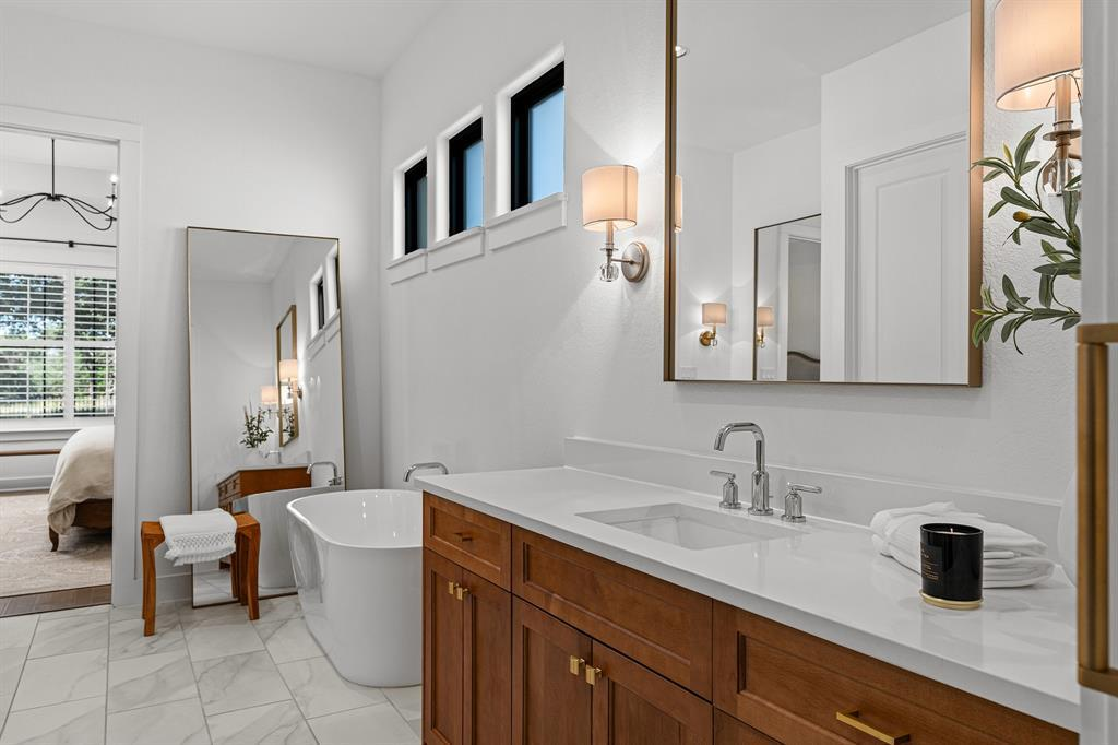 Primary bath — dual vanities, soaking tub, gold accents and marble tile