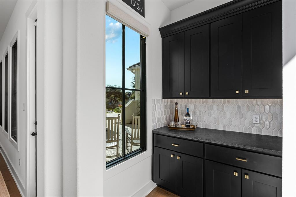 Butler's pantry with black cabinetry, hexagonal tile backsplash and gold hardware