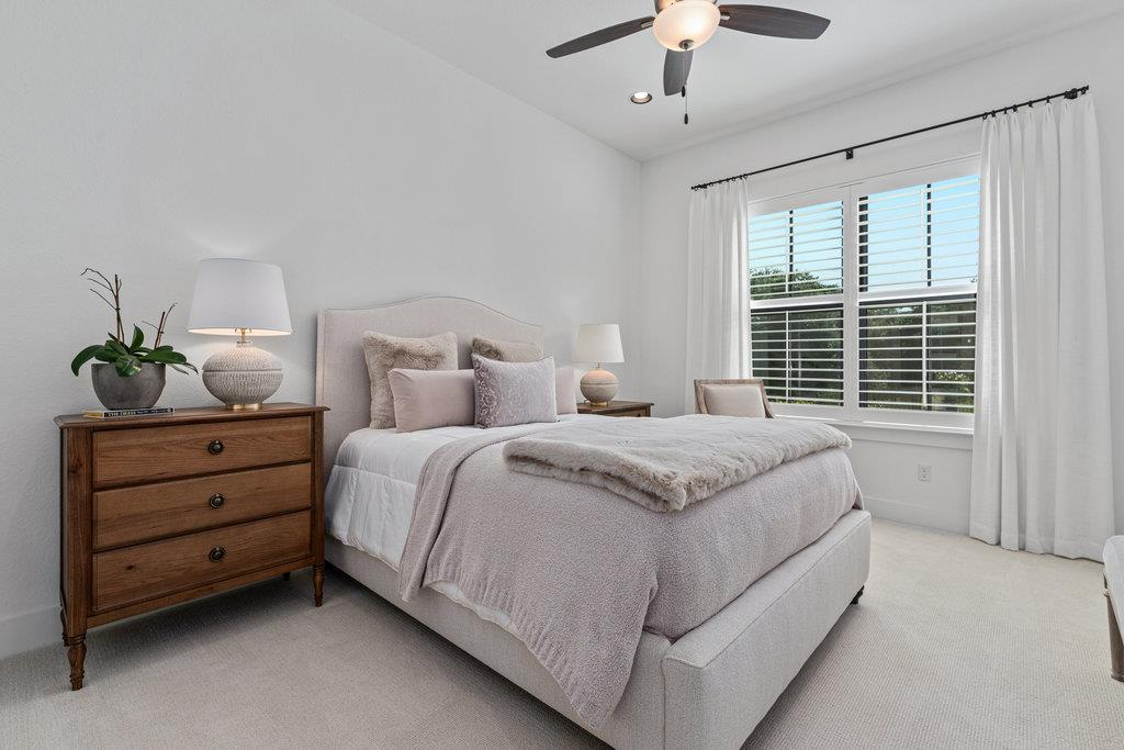 Secondary bedroom with upholstered bed, ceiling fan and plantation shutters