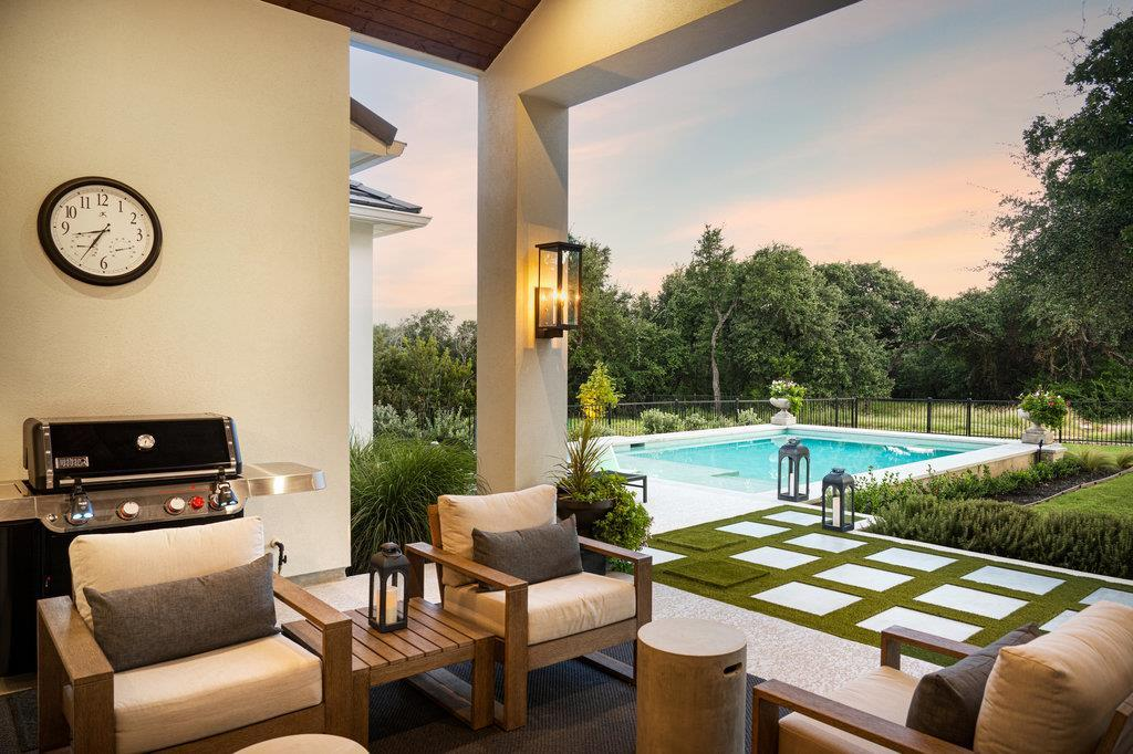 Covered patio with built-in grill, pool view and sunset sky