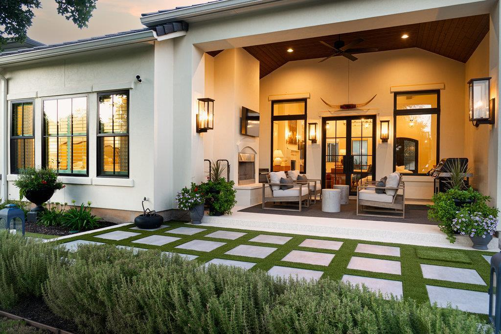 Rear exterior at dusk — covered patio with fireplace and stepping stone walkway