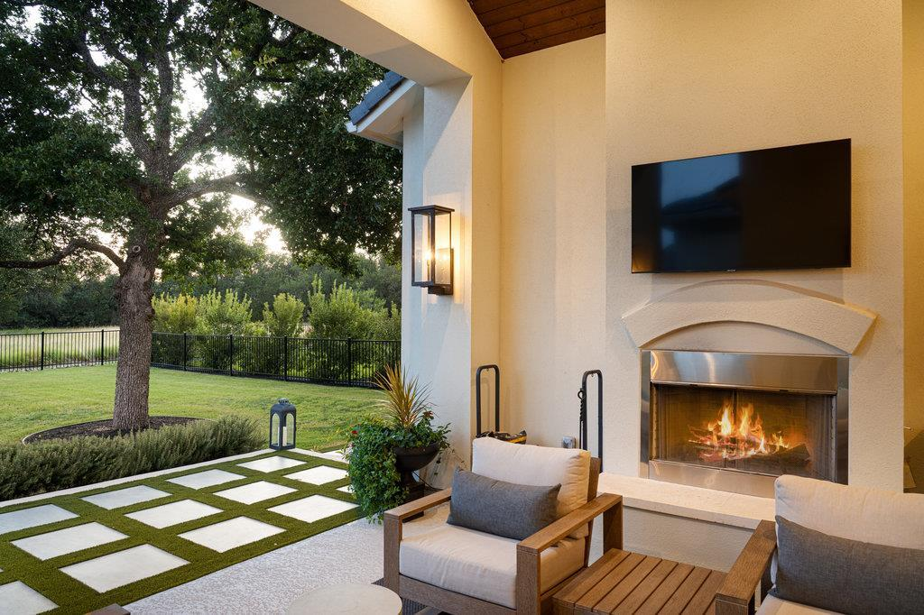 Covered patio fireplace with TV, outdoor seating and backyard views