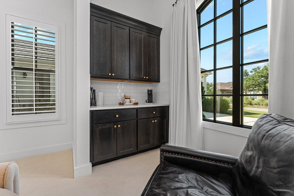 Casita kitchenette with dark cabinetry, subway tile backsplash and large windows